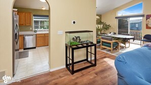 Una cucina con mobili in legno, un frigorifero in acciaio inossidabile e un acquario su un supporto nero.