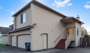 Une maison à deux étages avec un garage, une porte d’entrée et un escalier menant à l’entrée.
