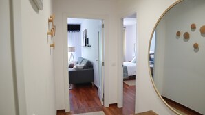Un couloir menant à un espace de vie comprenant un canapé et un lit.
