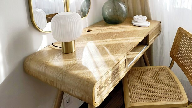 Une pièce comprenant un bureau en bois, une chaise et trois miroirs fixés au mur.