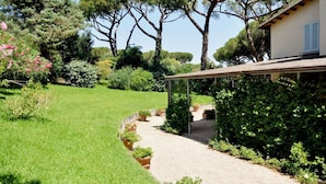 A garden pathway leading to a house with a pergola.