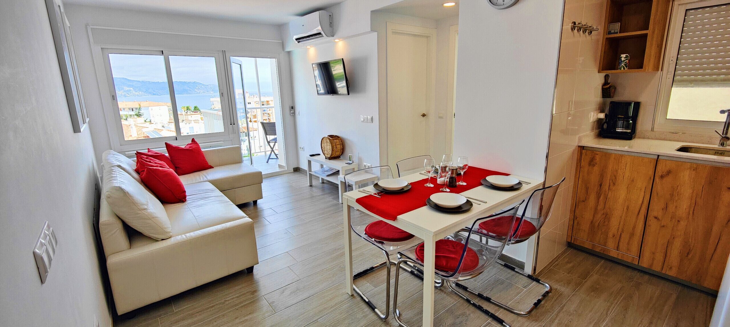 A modern apartment with a dining area, a living room with a sofa, and a kitchen.