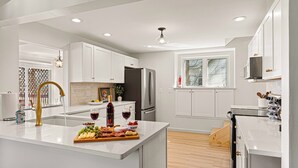 Une cuisine moderne avec des meubles blancs, un îlot central et un plancher en bois.