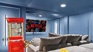 Une chambre dotée d’un grand lit, d’un appareil à pop-corn et d’un écran fixé au mur affichant le logo de Netflix.