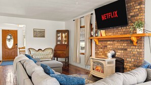 Un salon avec une cheminée, un téléviseur fixé au mur et un canapé.