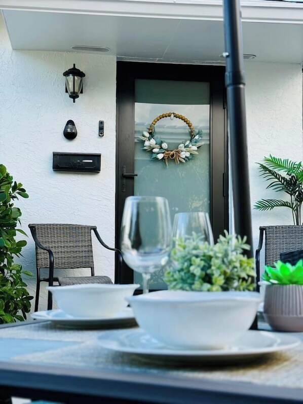 Un coin repas avec une table dressée pour deux personnes, un verre de vin et une guirlande décorative accrochée à la porte.