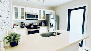 A modern kitchen with white cabinetry, stainless steel appliances, and a central island. - Quiet retreat near Coconut Grove + free parking (Miami)