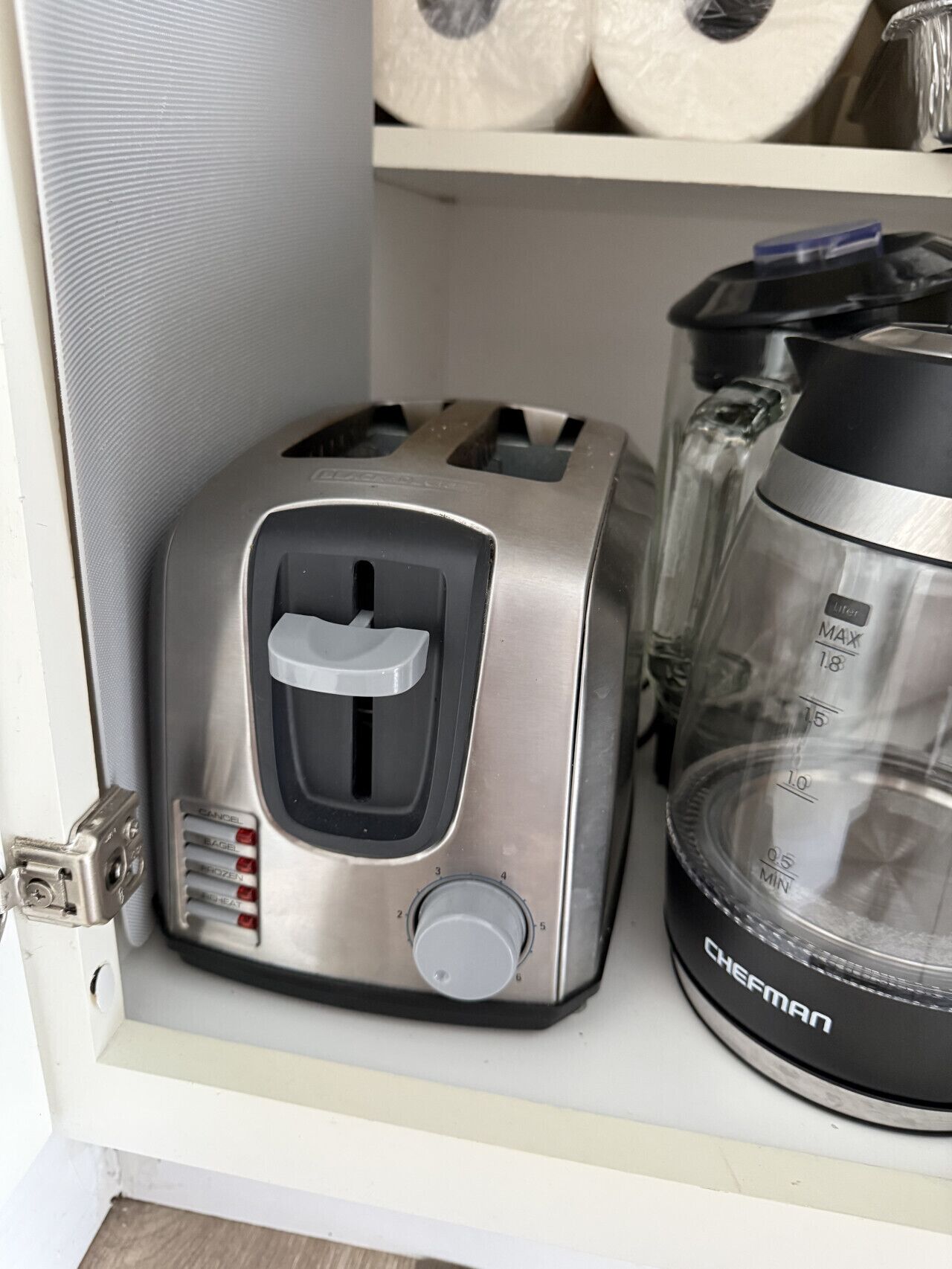 A compact kitchen with a toaster, a coffee maker, and a transparent container.
