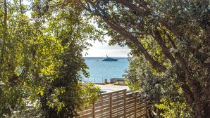 A view of a body of water with a boat, surrounded by trees and a wooden fence. - All day sun house with metres away from the golden sands of Onetangi Beach. (Waiheke Island)