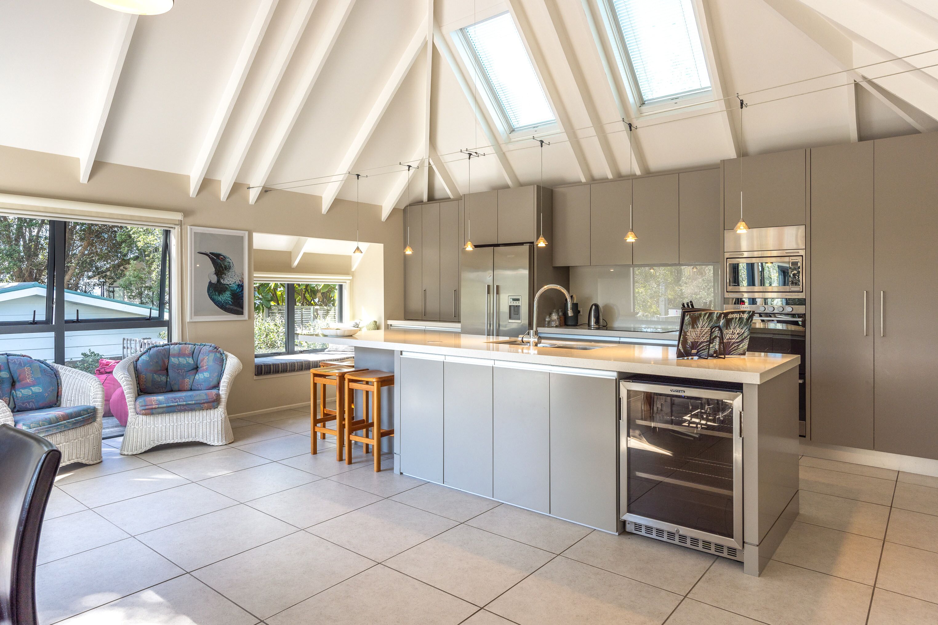 A modern kitchen with a large island, stainless steel appliances, and a skylight.