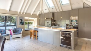 A modern kitchen with a large island, stainless steel appliances, and a skylight. - All day sun house with metres away from the golden sands of Onetangi Beach. (Waiheke Island)