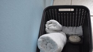 A black laundry basket containing rolled white towels and a soap bar. - Wake & Bake Vegas (Las Vegas)