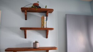Three wooden shelves against a wall, each holding a plant and books. - Wake & Bake Vegas (Las Vegas)