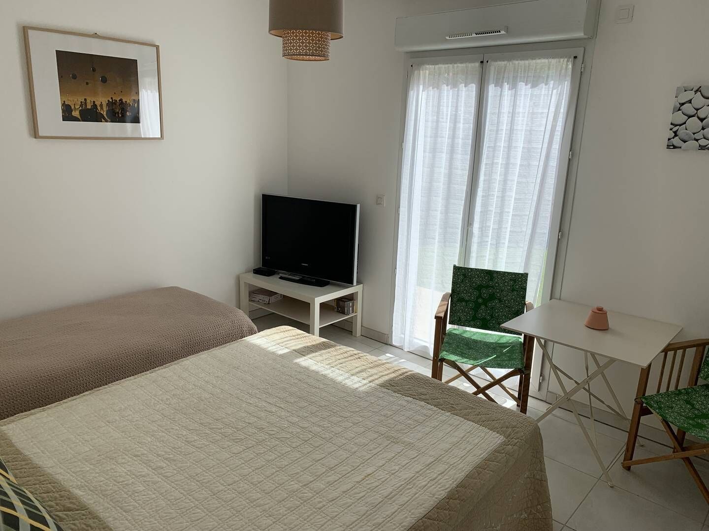 A bedroom with a bed, a TV on a stand, a chair, and a table.