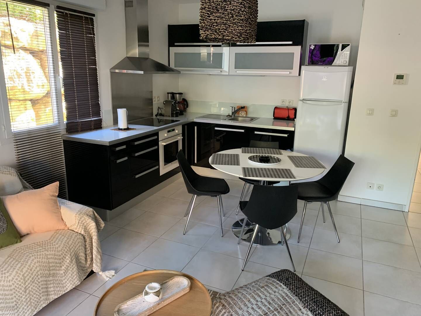 A compact kitchen with a dining area, featuring a microwave, oven, and a small refrigerator.
