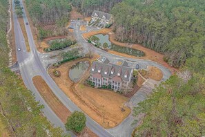 Stunning two-story house surrounded by a beautifully landscaped area with a pond and mature trees.