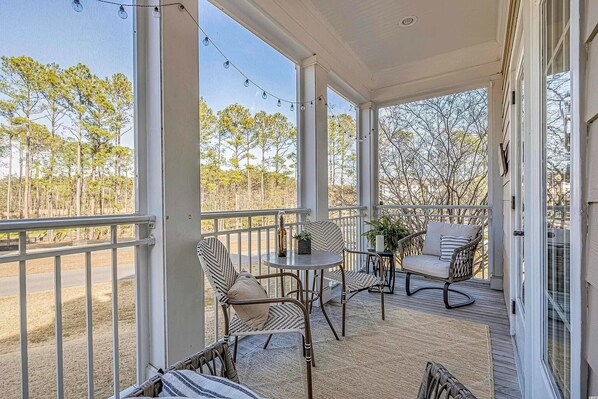 Relax in a serene outdoor space with a railing, chairs, and a table, surrounded by a natural landscape.