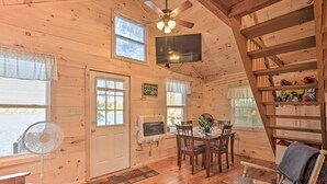 Ein Ferienhaus-Interieur mit Essbereich, einem Ventilator, einem Fernseher und einer Treppe.