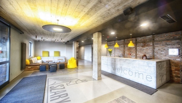A modern reception area with a 'Welcome' desk, seating area, and a 'Start Here' mat. - Residence Szary (Michalowice)