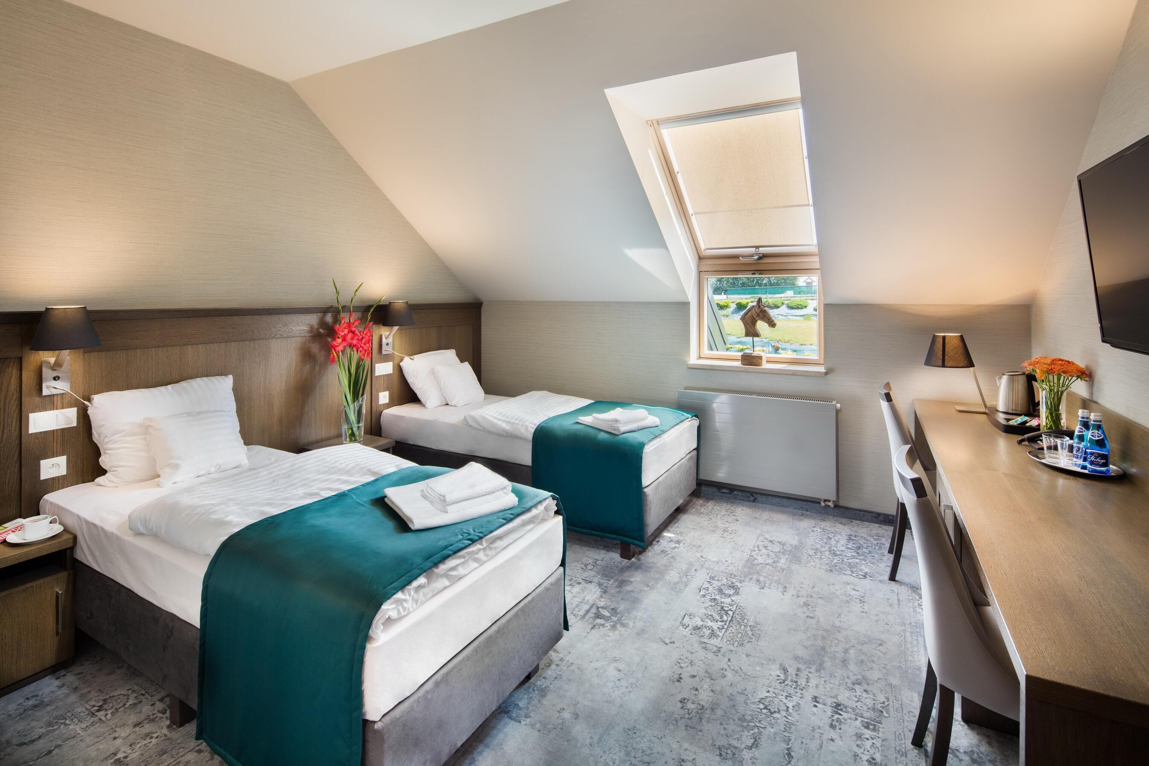 A hotel room with two beds, a desk, a window with a view, and a flat-screen TV.
