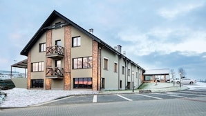 A modern building with a prominent balcony and multiple windows, situated in a snowy environment. - Residence Szary (Michalowice)
