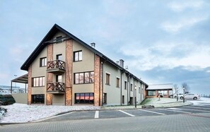 Un edificio moderno con un balcón destacado y múltiples ventanas, ubicado en un paisaje nevado.