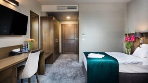 A hotel room with a bed, a desk with a chair, a TV, and a wardrobe. - Residence Szary (Michalowice)