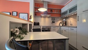 Una cocina compacta con comedor, que incluye estufa, pileta y electrodomésticos modernos.