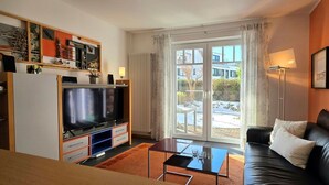 Una sala de estar con televisor, sofá y mesa de centro.