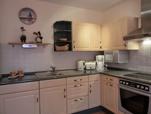 A kitchen with light-colored cabinets, a sink, a toaster, a coffee maker, and a microwave.
