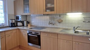 A modern kitchen with wooden cabinets, a built-in microwave, a toaster, and a stainless steel sink.
