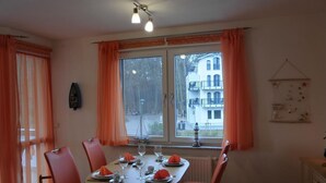 A dining area with a table set for four, a window with curtains, and a view of buildings outside.