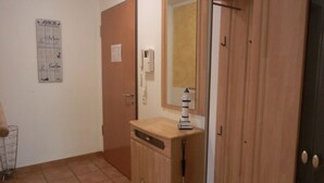 A hallway with a wooden cabinet, a mirror, and a small lighthouse decoration.