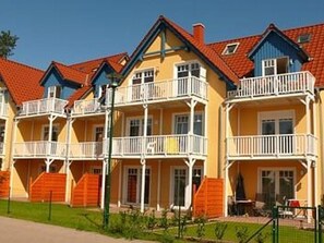 A row of yellow buildings with red roofs and white balconies.