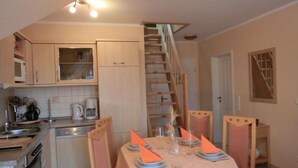 Una cocina con una mesa de comedor para cuatro personas, una escalera y un microondas.