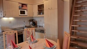 Cocina compacta con comedor, que incluye microondas, estufa y armarios.