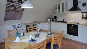 Eine kompakte Küche mit Essbereich, ausgestattet mit Herd, Backofen, Spüle und einer Wanduhr.
