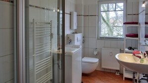 A bathroom with a glass shower enclosure, a toilet, a sink, and a window. - Apartment H 07 - Apartment near the beach for 4 + 1 people, with WLAN (Graal-Müritz)