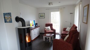 Ein modernes Wohnzimmer mit Kaminofen, roten Sofas, einem Couchtisch und einem Essbereich mit Schränken.