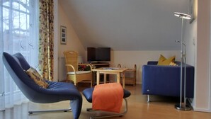 Tunnelmallinen olohuone, jossa on sininen sohva, sininen nojatuoli ja puinen pöytä, jonka päällä on televisio.