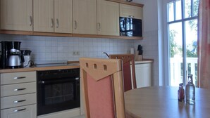 A kitchen with wooden cabinets, a microwave, a coffee maker, and a dining table with chairs. - Apartment T7 - 2-room apartment for 4 pers. on the upper floor. Close to the beach (Graal-Müritz)