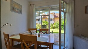 A dining area with a table and chairs, a radiator, and a window with curtains.