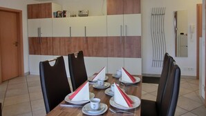 Un comedor con una mesa de madera dispuesta para cuatro personas, con platos, vasos y cubiertos.
