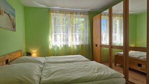 Una habitación con dos camas, un cuadro en la pared y una ventana con cortinas.