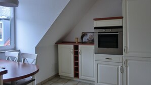 Uma cozinha com armários brancos, bancada de madeira e forno embutido.