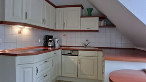 Uma cozinha compacta com armários brancos, lava-louças embutida e bancada de madeira.