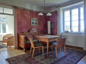 Ein gemütliches Zimmer mit einem Holztisch, Stühlen, einer Couch und einem gemusterten Teppich.