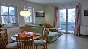 Una sala de estar moderna con comedor, ventanas grandes y vistas al exterior.