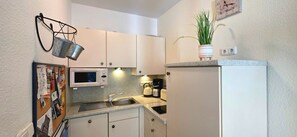 A compact kitchen with white cabinets, a microwave, a kettle, and a small sink. - Apartment i26 - 2-room apartment near the beach on the 1st floor for 3 pers. (Graal-Müritz)