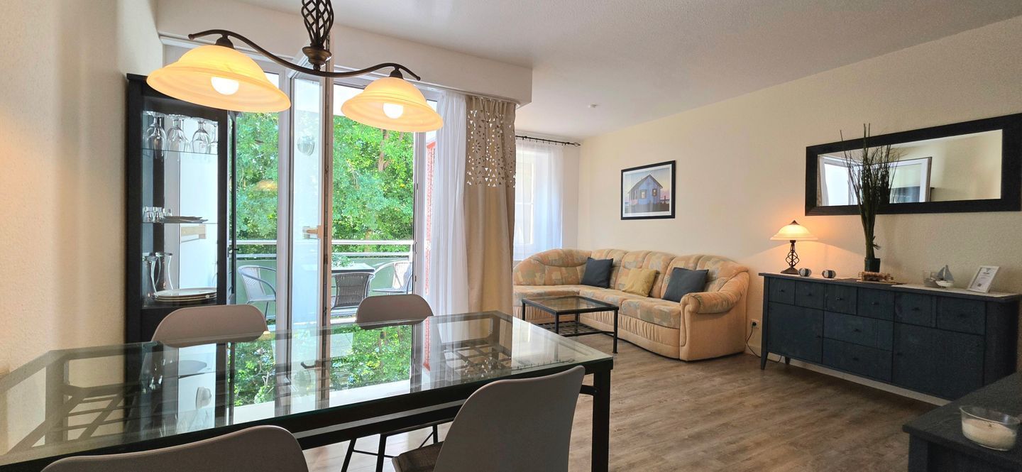 A living room with a glass dining table, a sofa, and a cabinet.
